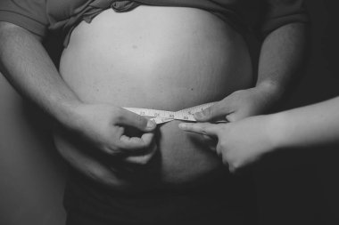 Asyalı şişman bir adam aynanın önünde vücuduna bakıyor. Aşırı göbek yağı, sağlıksız yaşam tarzı, diyet konsepti.