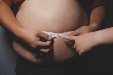 Asyalı şişman bir adam aynanın önünde vücuduna bakıyor. Aşırı göbek yağı, sağlıksız yaşam tarzı, diyet konsepti.