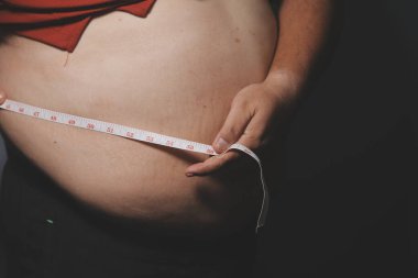 Asyalı şişman bir adam aynanın önünde vücuduna bakıyor. Aşırı göbek yağı, sağlıksız yaşam tarzı, diyet konsepti.