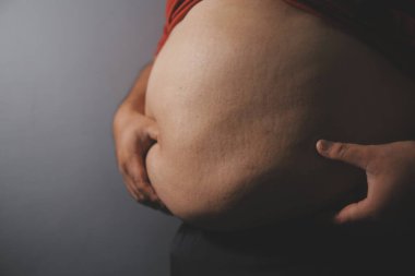 Asyalı şişman bir adam aynanın önünde vücuduna bakıyor. Aşırı göbek yağı, sağlıksız yaşam tarzı, diyet konsepti.