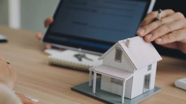 Emlakçı müşteriye ev almak için kontrat gösteriyor. Emlakçı, ev ya da ev satın alıyor..