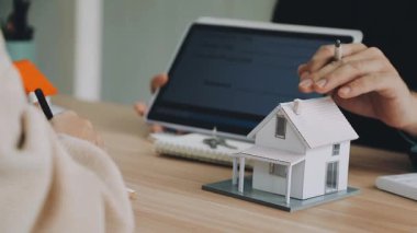 Emlakçı ev modelini ve sözleşmeyi müşteriye gösteriyor