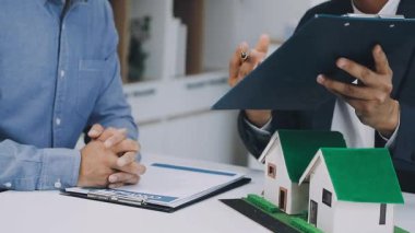 Arka planda ev modeli olan iş adamı el ele tutuşması modelini kapatın. iş kavramı.