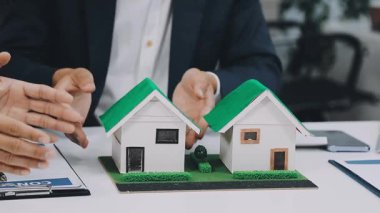 Ev modelinin anahtarlarını taşıyan iş adamı ve ev modelleri