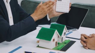 Ev modelini tutan ve elinde evin anahtarını gösteren bir iş adamı, emlakçı.