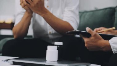 Dizüstü bilgisayar kullanırken elinde hap şişesi olan adama yaklaş.