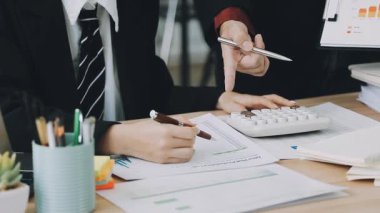 İş kadını hesap makinesi kullanıyor ve masaya mali belgeler yazıyor.