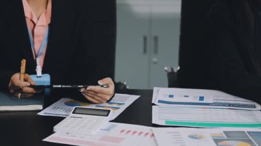 İş adamları masadaki mali verileri tartışıyor ve analiz ediyorlar.