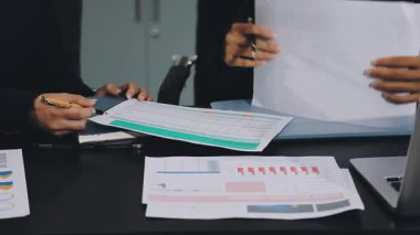 İş adamları ofis odasında mali verileri ve çizelgeleri tartışıyor.