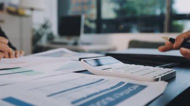 İş kadını ofis masasında hesap makinesiyle yazıyor.