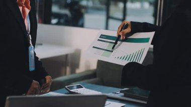 İş kadını laptopta çalışıyor ve modern ofiste belgelerle iş planını tartışıyor..