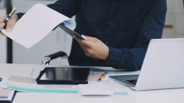 İşadamı ofiste dizüstü bilgisayarla ve belgelerle çalışıyor.