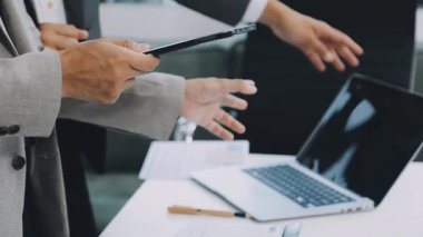 Ofiste çalışan genç iş adamları, ellerinde dizüstü bilgisayarlarıyla...