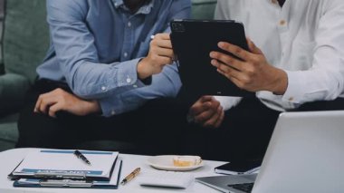 İş adamı ve kadın bir tablet ve bir defterle masada oturuyorlar..