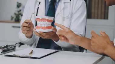 Diş hekimi dişini tedavi etmek için bir diş gösteriyor..