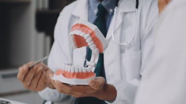 Doktor diş muayenehanesinde bir diş tutuyor.