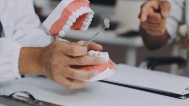 Yakın plan. Diş hekiminin elleri, dişçi kliniği modeli olan bir diş modelini tutuyor..