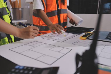 Endüstriyel mühendislerden oluşan bir ekip, fabrikadaki masada bulunan makine planlarını analiz ediyor. Fabrikada ya da üretim tesisinde çalışıyorum..