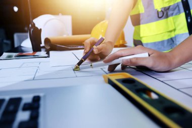 Endüstriyel mühendislerden oluşan bir ekip, fabrikadaki masada bulunan makine planlarını analiz ediyor. Fabrikada ya da üretim tesisinde çalışıyorum..