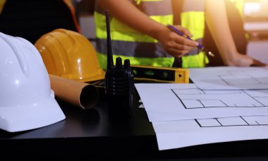 Endüstriyel mühendislerden oluşan bir ekip, fabrikadaki masada bulunan makine planlarını analiz ediyor. Fabrikada ya da üretim tesisinde çalışıyorum..