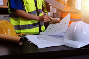 Endüstriyel mühendislerden oluşan bir ekip, fabrikadaki masada bulunan makine planlarını analiz ediyor. Fabrikada ya da üretim tesisinde çalışıyorum..