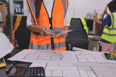 Endüstriyel mühendislerden oluşan bir ekip, fabrikadaki masada bulunan makine planlarını analiz ediyor. Fabrikada ya da üretim tesisinde çalışıyorum..