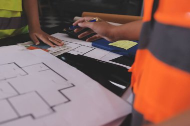 Endüstriyel mühendislerden oluşan bir ekip, fabrikadaki masada bulunan makine planlarını analiz ediyor. Fabrikada ya da üretim tesisinde çalışıyorum..