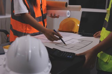 Endüstriyel mühendislerden oluşan bir ekip, fabrikadaki masada bulunan makine planlarını analiz ediyor. Fabrikada ya da üretim tesisinde çalışıyorum..