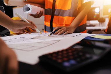 Endüstriyel mühendislerden oluşan bir ekip, fabrikadaki masada bulunan makine planlarını analiz ediyor. Fabrikada ya da üretim tesisinde çalışıyorum..