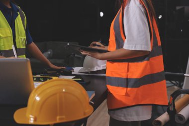 Endüstriyel mühendislerden oluşan bir ekip, fabrikadaki masada bulunan makine planlarını analiz ediyor. Fabrikada ya da üretim tesisinde çalışıyorum..