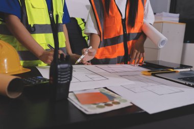 Endüstriyel mühendislerden oluşan bir ekip, fabrikadaki masada bulunan makine planlarını analiz ediyor. Fabrikada ya da üretim tesisinde çalışıyorum..