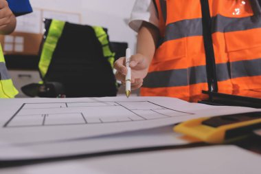 Endüstriyel mühendislerden oluşan bir ekip, fabrikadaki masada bulunan makine planlarını analiz ediyor. Fabrikada ya da üretim tesisinde çalışıyorum..