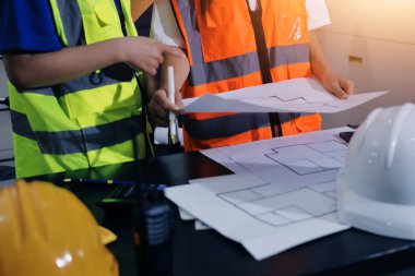 Endüstriyel mühendislerden oluşan bir ekip, fabrikadaki masada bulunan makine planlarını analiz ediyor. Fabrikada ya da üretim tesisinde çalışıyorum..