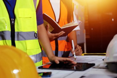 Endüstriyel mühendislerden oluşan bir ekip, fabrikadaki masada bulunan makine planlarını analiz ediyor. Fabrikada ya da üretim tesisinde çalışıyorum..