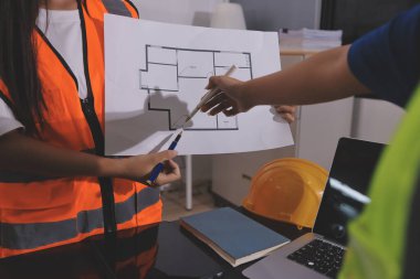 Endüstriyel mühendislerden oluşan bir ekip, fabrikadaki masada bulunan makine planlarını analiz ediyor. Fabrikada ya da üretim tesisinde çalışıyorum..