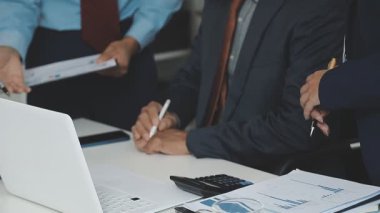 İş adamları laptopta çalışıyor ve modern işyerinde fikirleri tartışıyor.
