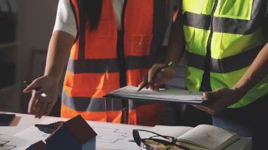 Genç bayan mühendis ya da mühendis sarı üniformalı ve güvenlik kasklı.