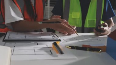 Genç Asyalı mimar mühendisi ofiste planla çalışıyor.