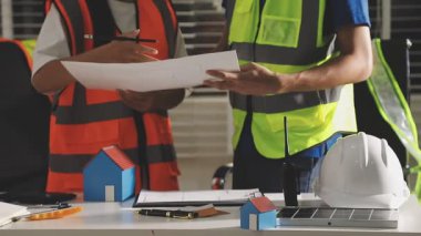 Genç Asyalı mühendis ofiste planlarla çalışıyor..