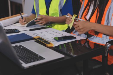 Endüstriyel mühendislerden oluşan bir ekip, fabrikadaki masada bulunan makine planlarını analiz ediyor. Fabrikada ya da üretim tesisinde çalışıyorum..