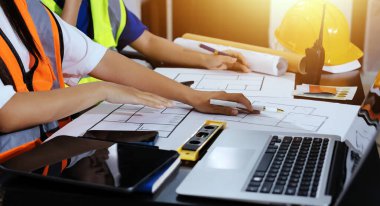 Endüstriyel mühendislerden oluşan bir ekip, fabrikadaki masada bulunan makine planlarını analiz ediyor. Fabrikada ya da üretim tesisinde çalışıyorum..