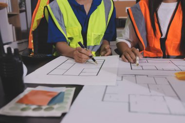 Endüstriyel mühendislerden oluşan bir ekip, fabrikadaki masada bulunan makine planlarını analiz ediyor. Fabrikada ya da üretim tesisinde çalışıyorum..