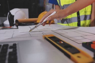 Endüstriyel mühendislerden oluşan bir ekip, fabrikadaki masada bulunan makine planlarını analiz ediyor. Fabrikada ya da üretim tesisinde çalışıyorum..