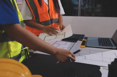 Endüstriyel mühendislerden oluşan bir ekip, fabrikadaki masada bulunan makine planlarını analiz ediyor. Fabrikada ya da üretim tesisinde çalışıyorum..