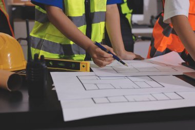 Endüstriyel mühendislerden oluşan bir ekip, fabrikadaki masada bulunan makine planlarını analiz ediyor. Fabrikada ya da üretim tesisinde çalışıyorum..