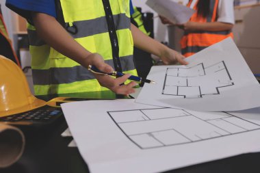 Endüstriyel mühendislerden oluşan bir ekip, fabrikadaki masada bulunan makine planlarını analiz ediyor. Fabrikada ya da üretim tesisinde çalışıyorum..