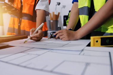 Endüstriyel mühendislerden oluşan bir ekip, fabrikadaki masada bulunan makine planlarını analiz ediyor. Fabrikada ya da üretim tesisinde çalışıyorum..