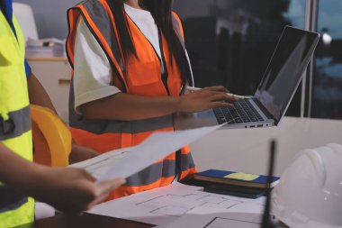 Endüstriyel mühendislerden oluşan bir ekip, fabrikadaki masada bulunan makine planlarını analiz ediyor. Fabrikada ya da üretim tesisinde çalışıyorum..