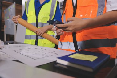 Endüstriyel mühendislerden oluşan bir ekip, fabrikadaki masada bulunan makine planlarını analiz ediyor. Fabrikada ya da üretim tesisinde çalışıyorum..