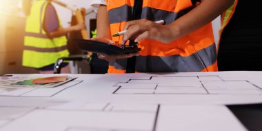 Endüstriyel mühendislerden oluşan bir ekip, fabrikadaki masada bulunan makine planlarını analiz ediyor. Fabrikada ya da üretim tesisinde çalışıyorum..